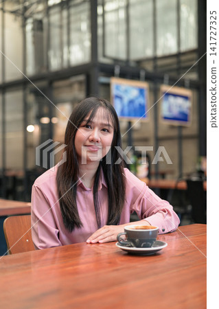 Portrait of a Confident Asian Woman Sitting in a Cafe with a Cup of Coffee Portrait of a Confident Asian Woman Sitting in a Cafe with a Cup of Coffee 141727325