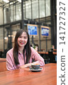Portrait of a Confident Asian Woman Sitting in a Cafe with a Cup of Coffee 141727327