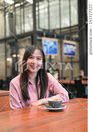 Portrait of a Confident Asian Woman Sitting in a Cafe with a Cup of Coffee Portrait of a Confident Asian Woman Sitting in a Cafe with a Cup of Coffee 141727327