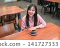 High Angle View of a Smiling Asian Woman Looking Away in a Cafe with Coffee 141727333