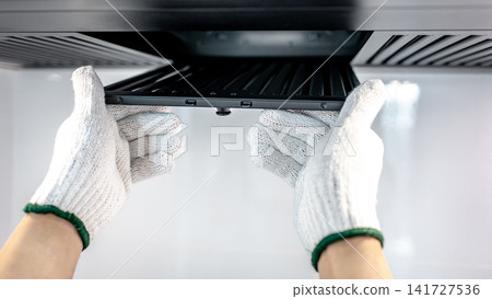 Male hand technician removing range hood filter from modern cooker hood Male hand technician removing range hood filter from modern cooker hood 141727536