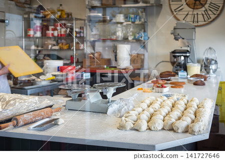 Raw bread dough portions on a table in a commercial bakery. Food production facility Raw bread dough portions on a table in a commercial bakery. Food production facility 141727646