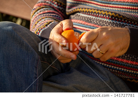 Person peeling a fresh orange for a healthy snack Person peeling a fresh orange for a healthy snack 141727781