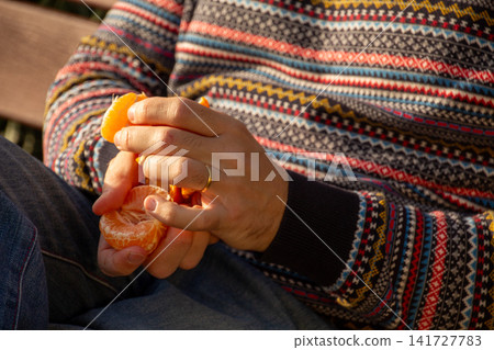 Person peeling a fresh orange for a healthy snack Person peeling a fresh orange for a healthy snack 141727783