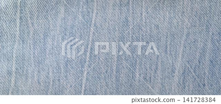 Close up of light blue denim with a fine diagonal twill weave and lighter threads creating a faded, distressed effect. Close up of light blue denim with a fine diagonal twill weave and lighter threads creating a faded, distressed effect. 141728384