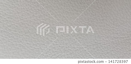 Top down close up of white or off-white grained leather with a consistent surface of small, irregular raised bumps and depressions characteristic of natural hide Top down close up of white or off-white grained leather with a consistent surface of small, irregular raised bumps and depressions characteristic of natural hide 141728397