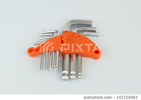 Set of metal hex keys in different sizes arranged in a bright orange plastic holder on a light background. Set of metal hex keys in different sizes arranged in a bright orange plastic holder on a light background. 141728903