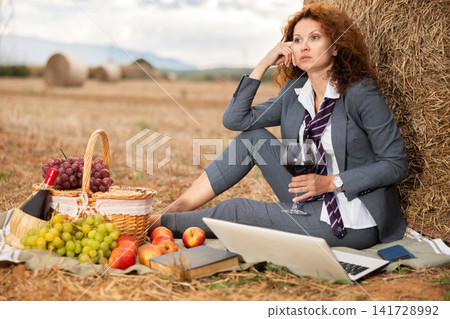 Tired business woman drinking wine during country picnic Tired business woman drinking wine during country picnic 141728992