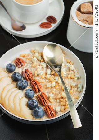 Oatmeal. Bowl of oatmeal porridge with blackberry, bananas and chia seeds on gray concrete old table background. Top view in flat lay style. Natural ingredients. Hot healthy breakfast and diet food Oatmeal. Bowl of oatmeal porridge with blackberry, bananas and chia seeds on gray concrete old table background. Top view in flat lay style. Natural ingredients. Hot healthy breakfast and diet food 141728993