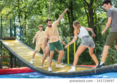 Group trying to cross moving swinging bridge over trampoline Group trying to cross moving swinging bridge over trampoline 141729097