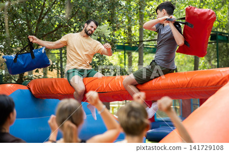 European guys fight on bags while sitting on a log European guys fight on bags while sitting on a log 141729108