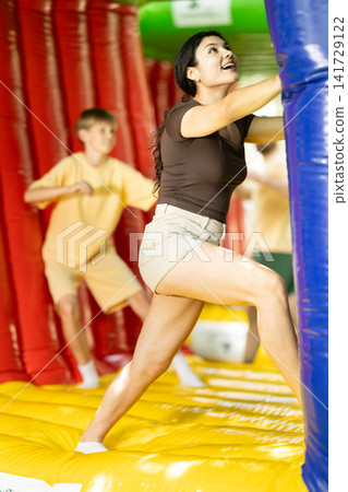Woman and boy inside cube trampoline pushing and moving it together Woman and boy inside cube trampoline pushing and moving it together 141729122