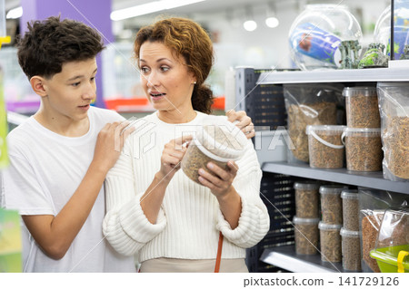 Woman with teenage son choosing pelleted food for pet turtle in shop Woman with teenage son choosing pelleted food for pet turtle in shop 141729126