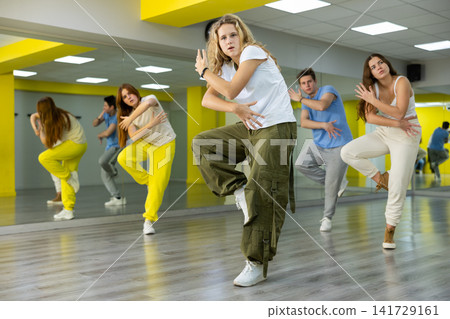 Class of expressive teenagers dancing and practicing new movements in dance hall. Sport, dance and urban culture concept Class of expressive teenagers dancing and practicing new movements in dance hall. Sport, dance and urban culture concept 141729161