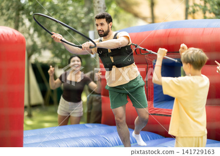 European man stands on an inflatable attraction and he tries to put on a ring European man stands on an inflatable attraction and he tries to put on a ring 141729163