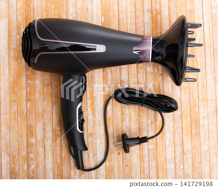Black blow dryer on wooden surface Black blow dryer on wooden surface 141729198