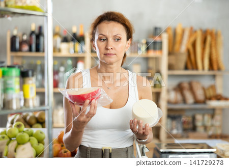 Adult woman choosing cheese in grocery store Adult woman choosing cheese in grocery store 141729278