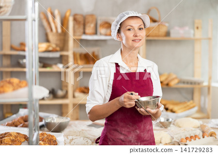 Adult female baker whipping dough Adult female baker whipping dough 141729283