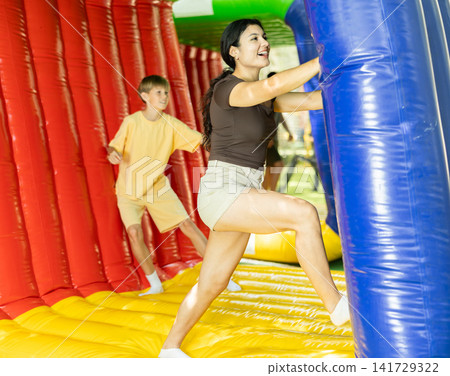 Friends compete against each other at an amusement park, trying to complete distance using inflatable balloons 141729322