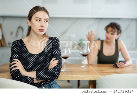 Two women have unpleasant conversation in dining room 141729334
