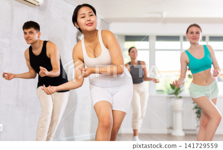 Positive young woman practicing dance positions during workout session Positive young woman practicing dance positions during workout session 141729559
