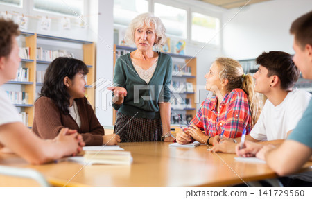 Brainstorming teenagers students and elderly teacher at library Brainstorming teenagers students and elderly teacher at library 141729560