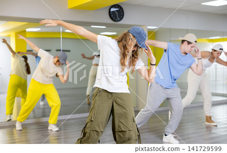 Cool sportive teenagers in casual wear practicing new moves during dance training together in studio Cool sportive teenagers in casual wear practicing new moves during dance training together in studio 141729599