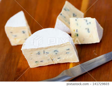 Slices of blue cheese on wooden cutting board Slices of blue cheese on wooden cutting board 141729603