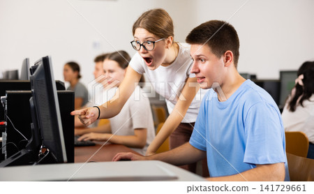 Smiling teenagers using computer during computer science lesson Smiling teenagers using computer during computer science lesson 141729661