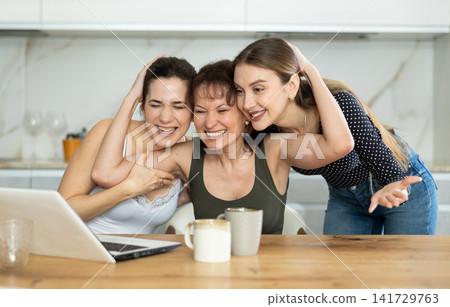 Three happy middle-aged woman expressing joy for winning in the kitchen Three happy middle-aged woman expressing joy for winning in the kitchen 141729763