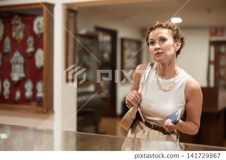 Interested woman examining collection of artifacts in historical museum Interested woman examining collection of artifacts in historical museum 141729867