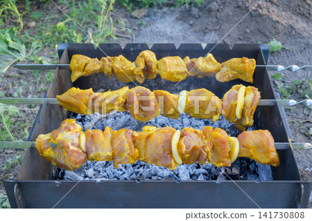 three skewers with appetizing marinated meat barbecue cooking on grill with coals outdoors three skewers with appetizing marinated meat barbecue cooking on grill with coals outdoors 141730808