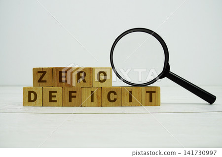 ZERO DEFICIT alphabet letters with magnifying glass on wooden background ZERO DEFICIT alphabet letters with magnifying glass on wooden background 141730997
