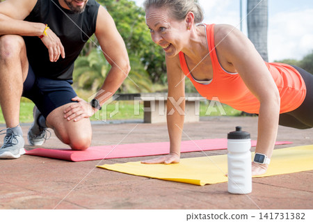 Woman doing push ups with personal trainer Woman doing push ups with personal trainer 141731382