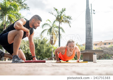 Woman doing push ups with personal trainer Woman doing push ups with personal trainer 141731383