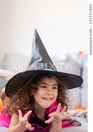 Little girl dressed as a witch lying on sofa for Halloween Little girl dressed as a witch lying on sofa for Halloween 141731403