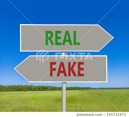 Real or fake words symbol. Concept words Fake and Real on beautiful grey road sign. Beautiful blue sky background. Business and real or fake concept. Copy space. Real or fake words symbol. Concept words Fake and Real on beautiful grey road sign. Beautiful blue sky background. Business and real or fake concept. Copy space. 141731471