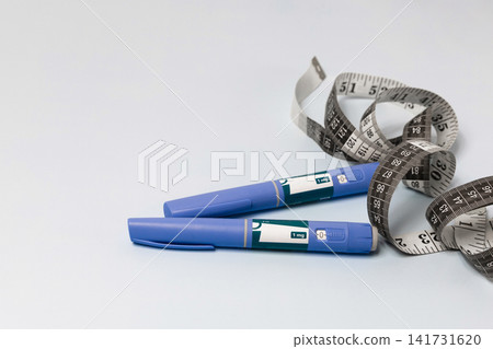 Ozempic pens with measuring tape illustrating slimming treatment. Ozempic pens with measuring tape illustrating slimming treatment. 141731620