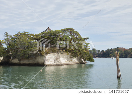 A serene scene at Matsuyama, featuring a traditional Japanese pavilion perched on the edge of a rocky island surrounded by calm waters under a soft blue sky with wispy clouds. A serene scene at Matsuyama, featuring a traditional Japanese pavilion perched on the edge of a rocky island surrounded by calm waters under a soft blue sky with wispy clouds. 141731667