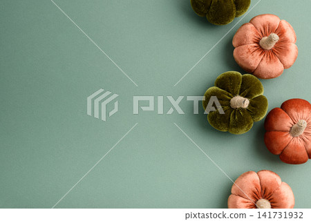 Soft fabric pumpkins in autumnal colors arranged on a plain background for seasonal decoration Soft fabric pumpkins in autumnal colors arranged on a plain background for seasonal decoration 141731932