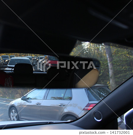 View from the car of a traffic jam in the rearview mirror and one car trying to overtake on the roadside. Violations of traffic rules during a traffic jam View from the car of a traffic jam in the rearview mirror and one car trying to overtake on the roadside. Violations of traffic rules during a traffic jam 141732001