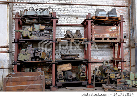 Metal shelving units storing heavy machine parts and industrial equipment components in a workshop Metal shelving units storing heavy machine parts and industrial equipment components in a workshop 141732034