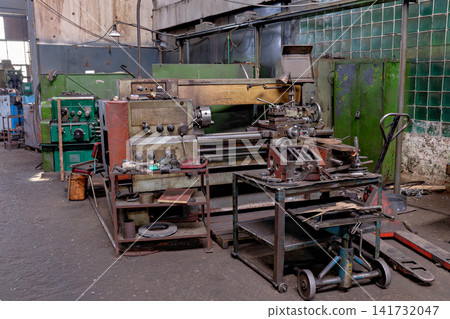 Old industrial metal turning lathe machine with work table in factory Old industrial metal turning lathe machine with work table in factory 141732047