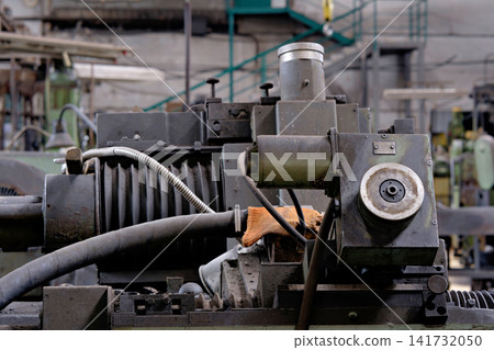 Vintage heavy industrial machine detail with flexible hose metal wheel and bellow guard in factory Vintage heavy industrial machine detail with flexible hose metal wheel and bellow guard in factory 141732050