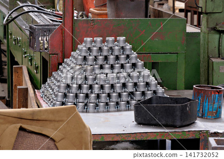 Stacked pyramid of shiny metal manufactured metal parts on table inside industrial factory workshop Stacked pyramid of shiny metal manufactured metal parts on table inside industrial factory workshop 141732052