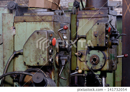 Vintage green industrial drilling machinery heads with control levers and red handles in factory Vintage green industrial drilling machinery heads with control levers and red handles in factory 141732054