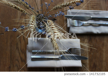 Craft Napkins With Old Family Forks And Knives For Dinner On A Table Decorated With Ikebana Of Dried Wheat Ears And Lavender Twigs Craft Napkins With Old Family Forks And Knives For Dinner On A Table Decorated With Ikebana Of Dried Wheat Ears And Lavender Twigs 141732105