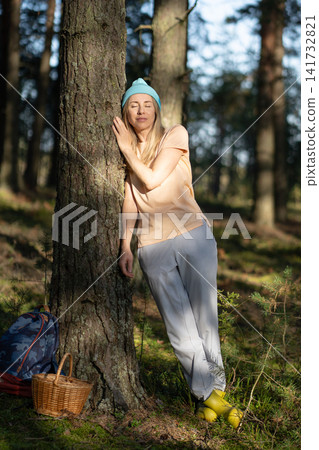 Loving nature purity. Relaxed woman leaning on tree trunk, rest after walk in in autumn forest. Loving nature purity. Relaxed woman leaning on tree trunk, rest after walk in in autumn forest. 141732821