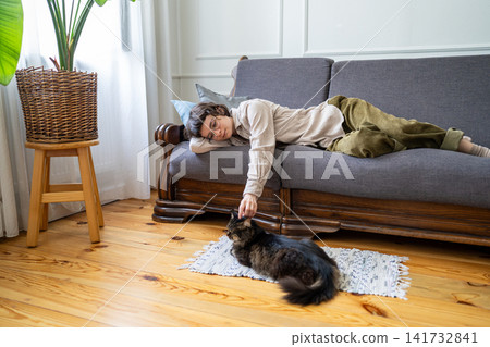 Tranquil relaxed woman comfortably lying on couch enjoying lazy day and time with domestic cat. Tranquil relaxed woman comfortably lying on couch enjoying lazy day and time with domestic cat. 141732841