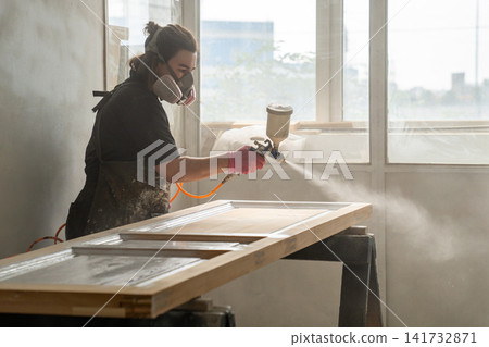 Restoration workshop process, craftsperson in paint booth finishing renovation vintage wooden door. 141732871